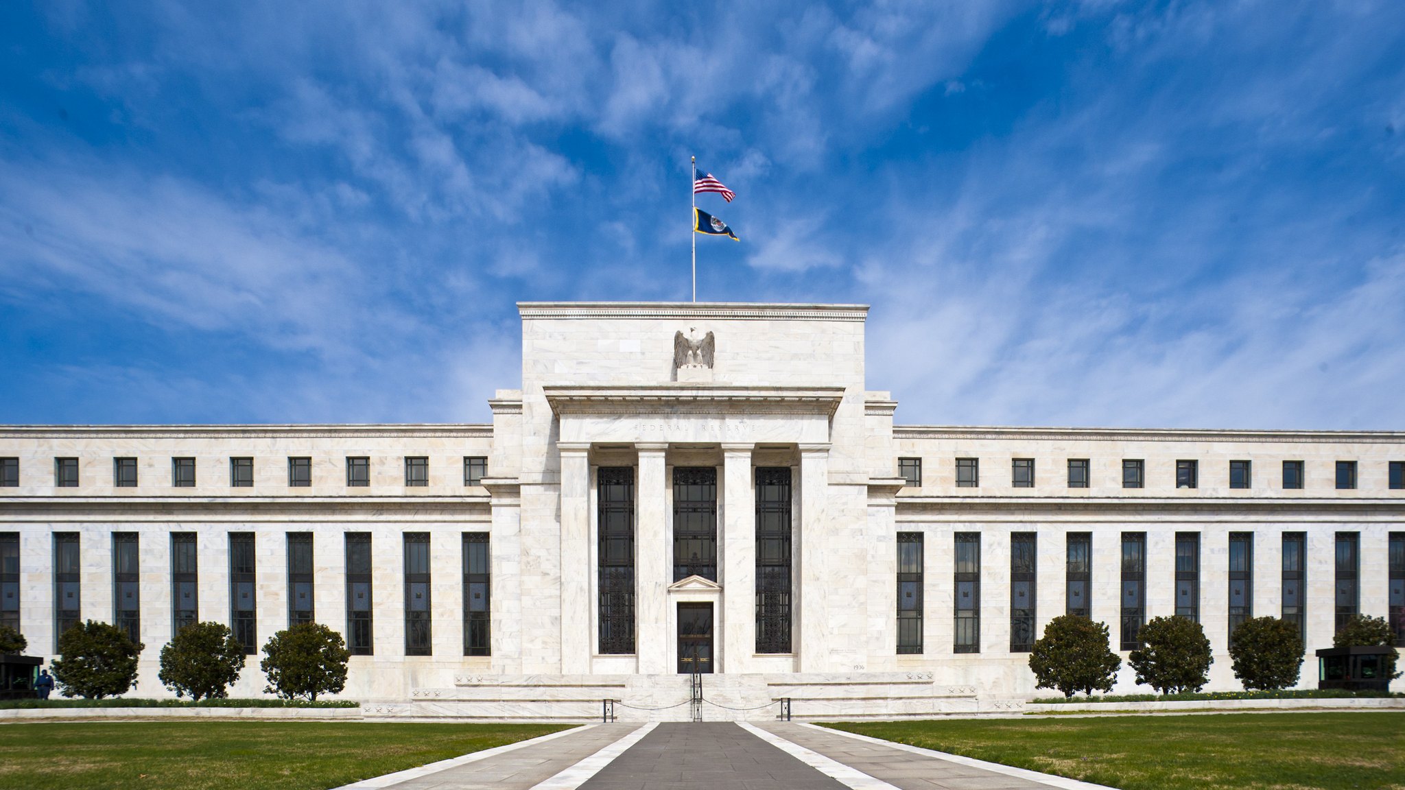 The Eccles Building, headquarters of the Federal Reserve Board in Washington, DC, with its white marble facade, flagpole and lawn.