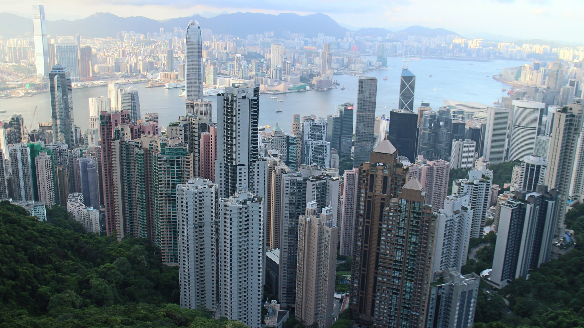 Daytime view over the skyscrapers of Hong Kong Island and Victoria Harbour, seen from high ground behind the city.