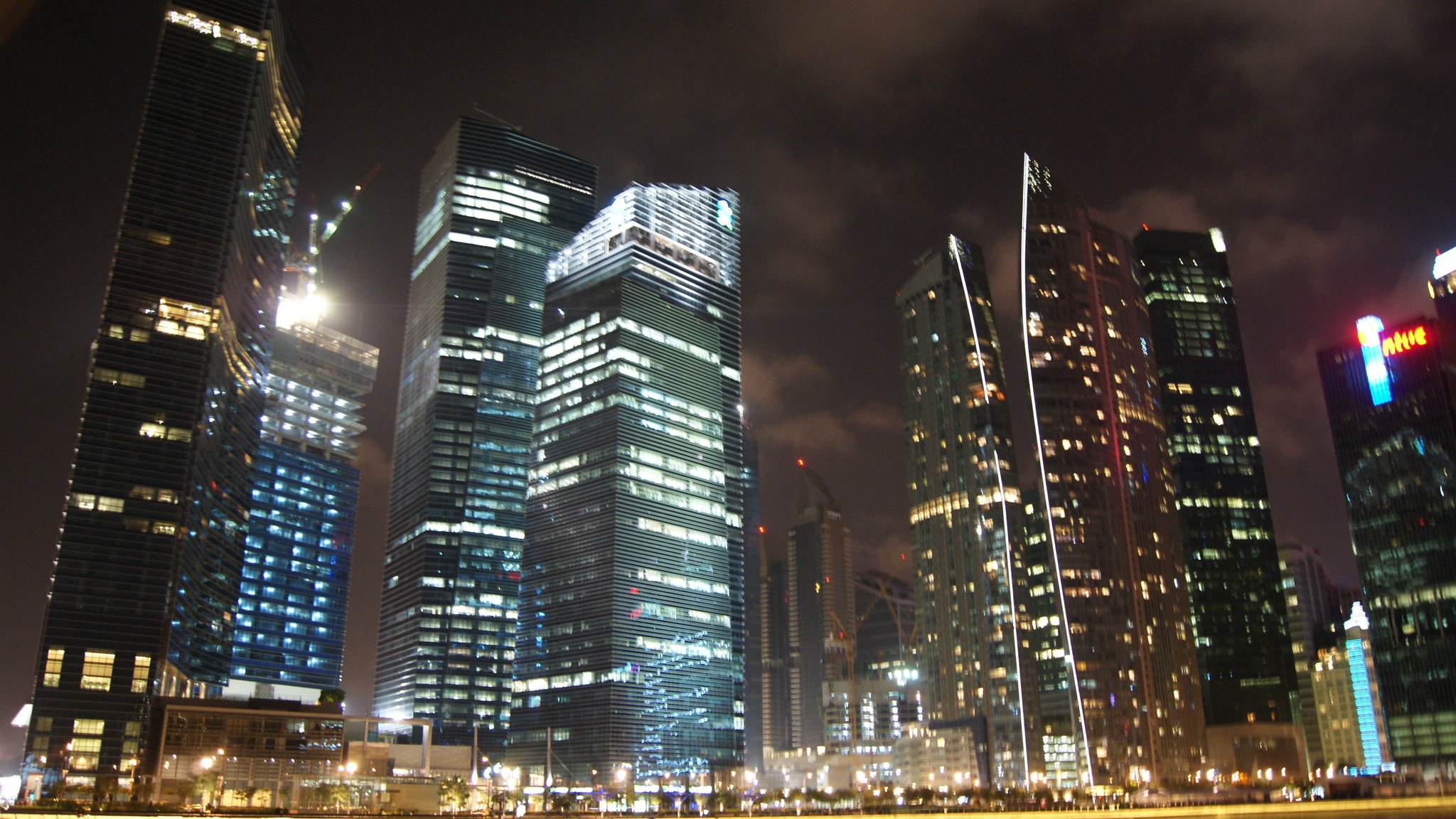 Marina Bay Financial Centre towers and The Sail at Marina Bay in Singapore, lit up at night.