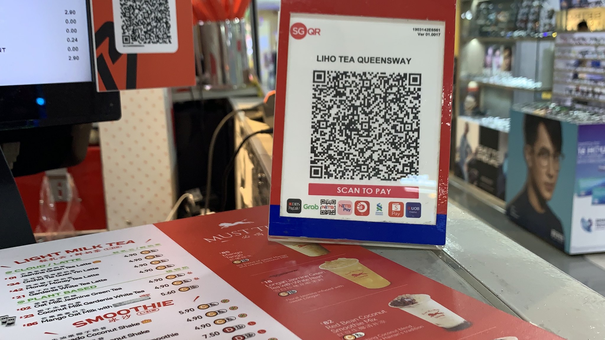 An SGQR code sign for NETS payments on a counter at a bubble tea shop in Queensway Shopping Centre, Singapore.