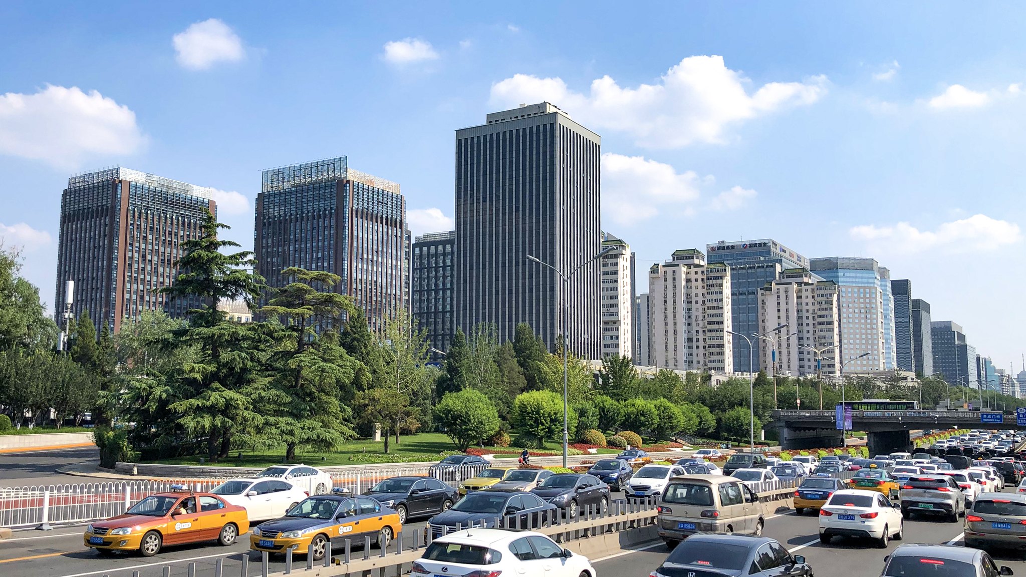 Office towers on Beijing's Financial Street seen from Fuchengmen, with taxis and parked cars in the foreground.